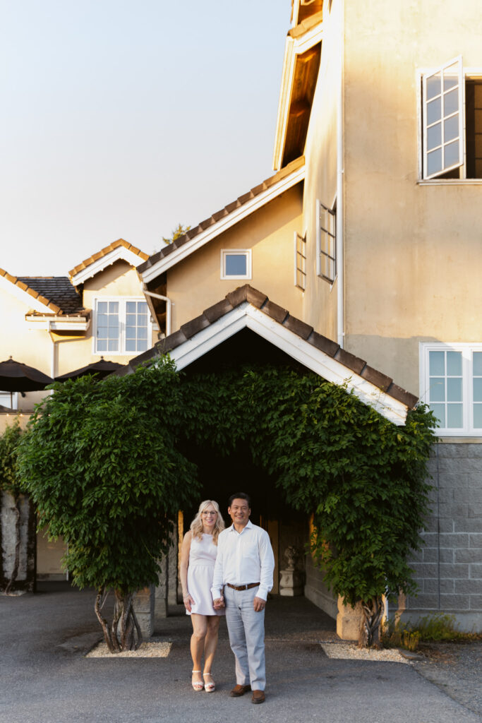 Bride and groom smiling together outside the chateau during golden hour portraits.