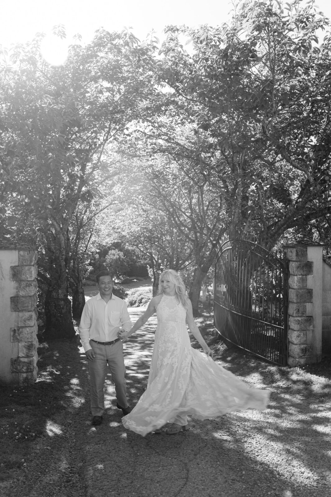 Bride and groom walking by the front gate during black and white portraits at Chateau Lill.