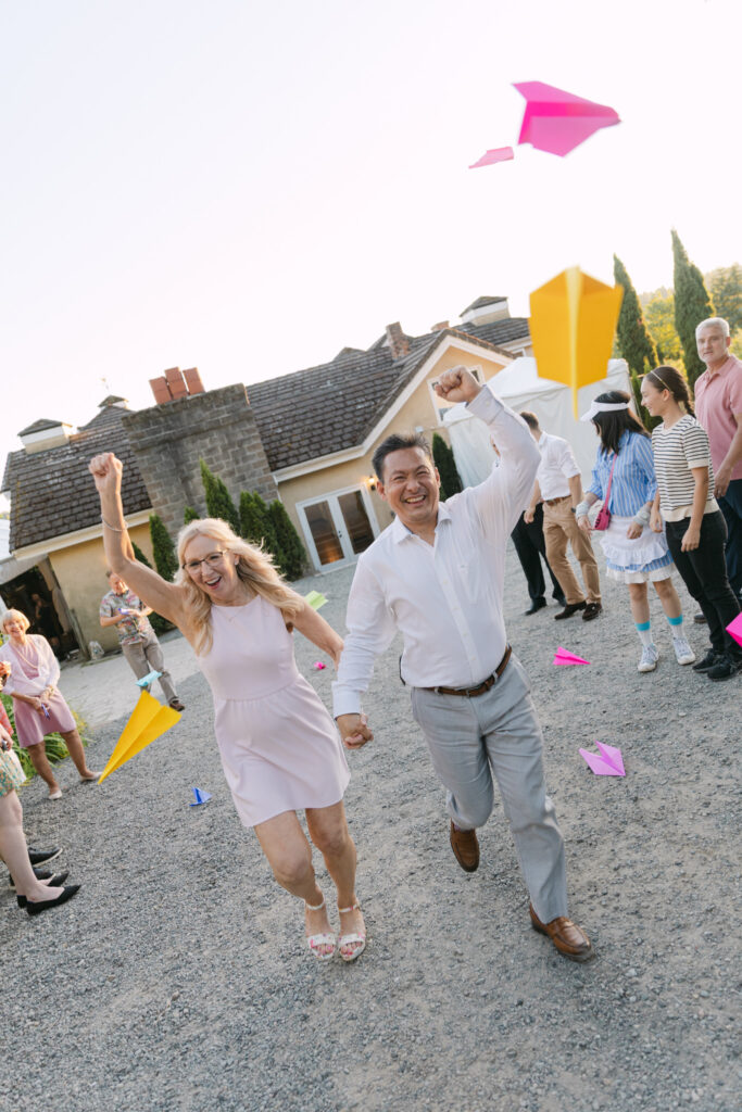 Bride and groom celebrating as guests throw paper airplanes at Chateau Lill.