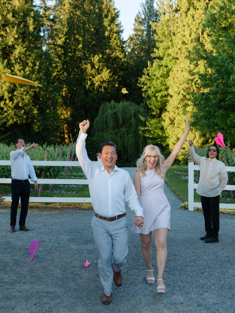 Bride and groom running through paper airplanes during their Chateau Lill wedding reception.