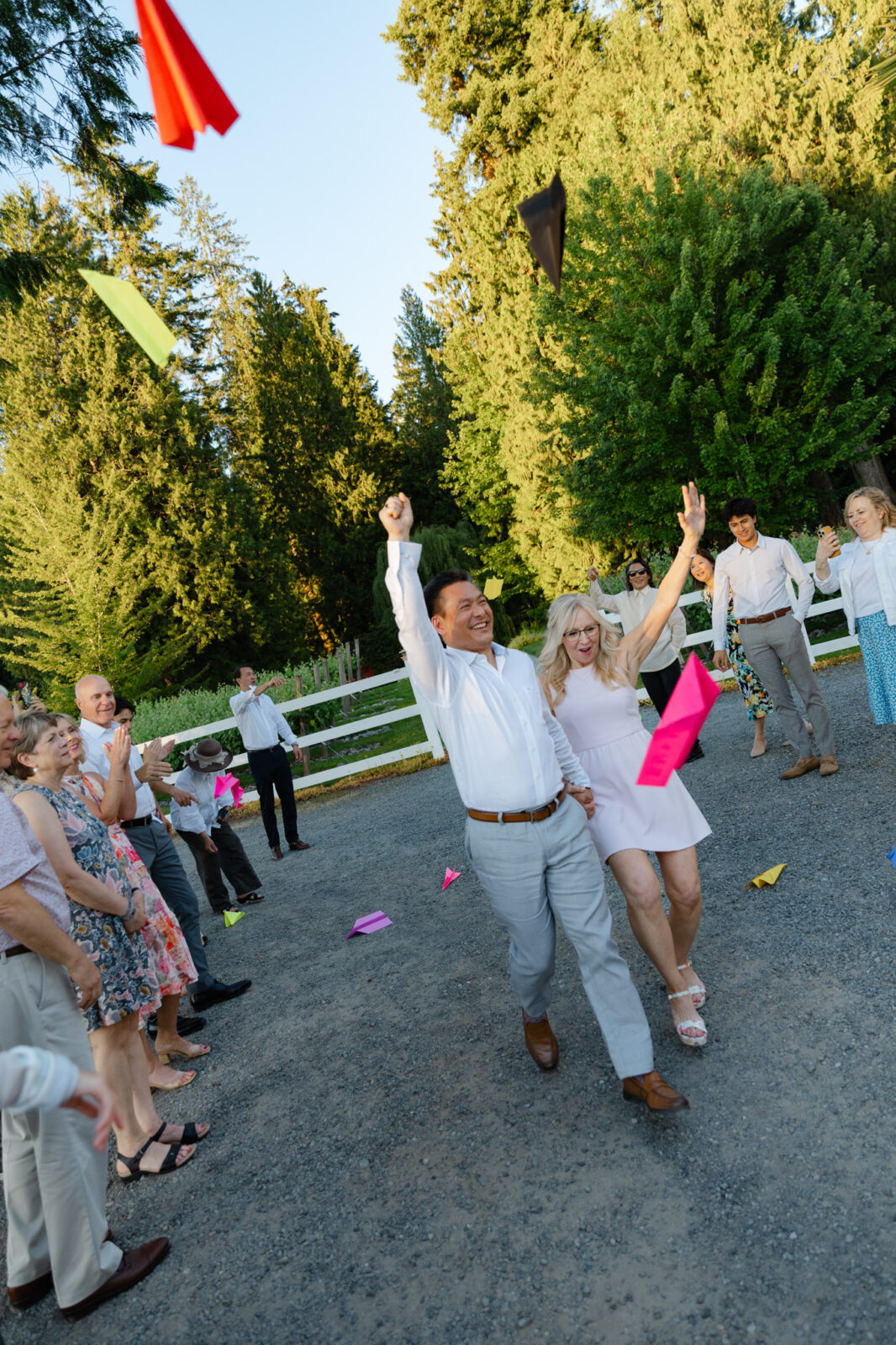 Bride and groom celebrating as guests throw paper airplanes at Chateau Lill.