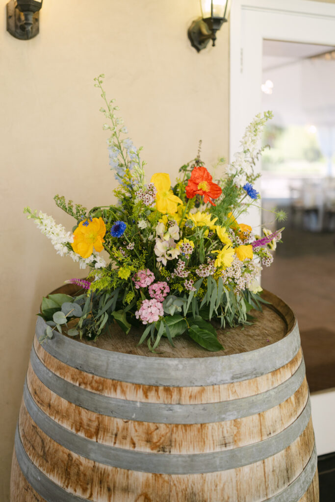 Colorful summer floral arrangement by Lilly and the Bee on a wine barrel at Chateau Lill.