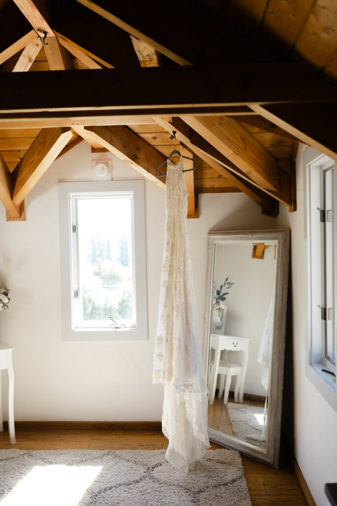 Wedding dress hanging from wooden beams inside the Terrace Suite at Chateau Lill.