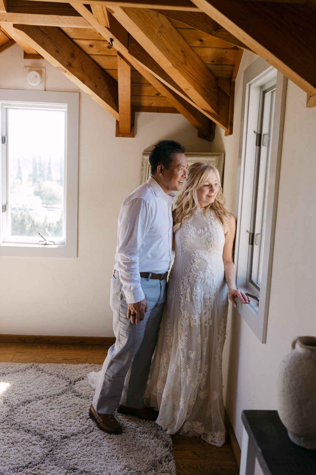 Bride and groom standing together by the window inside the Terrace Suite at Chateau Lill.