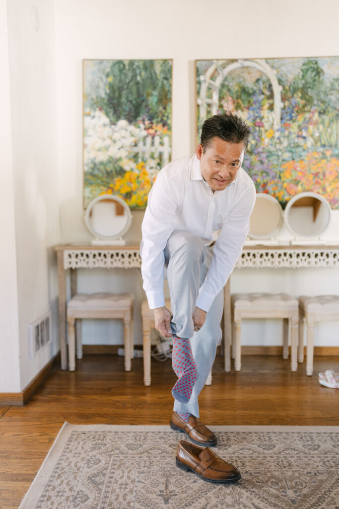 Groom putting on socks while getting ready inside the Terrace Suite at Chateau Lill.