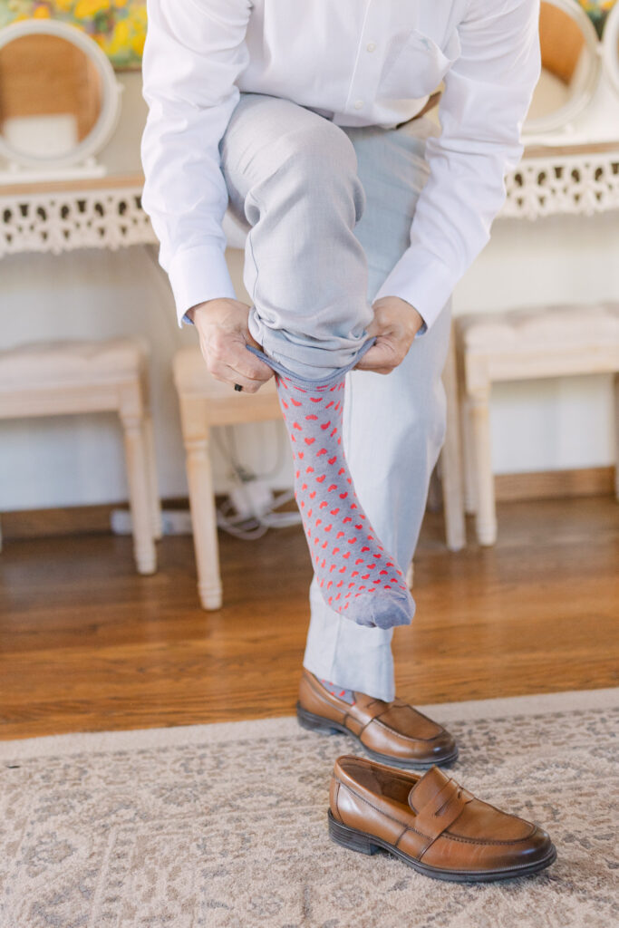Groom putting on socks while getting ready inside the Terrace Suite at Chateau Lill.