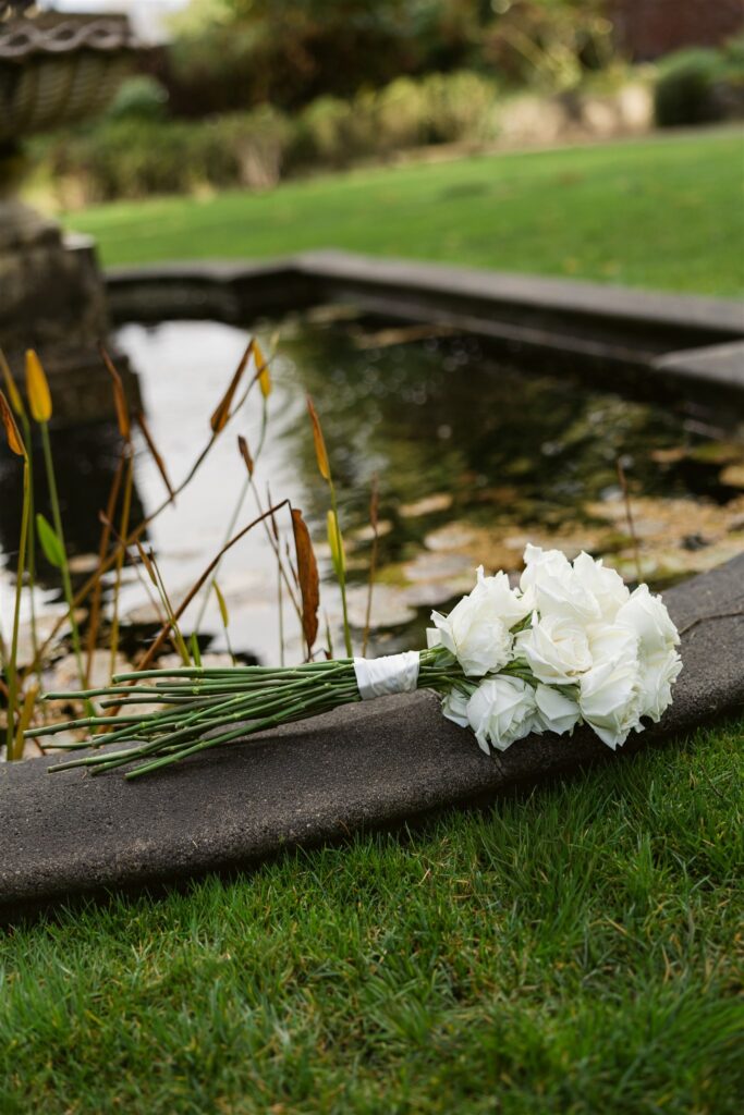 Brides wedding bouquet resting by the fountain outdoors.