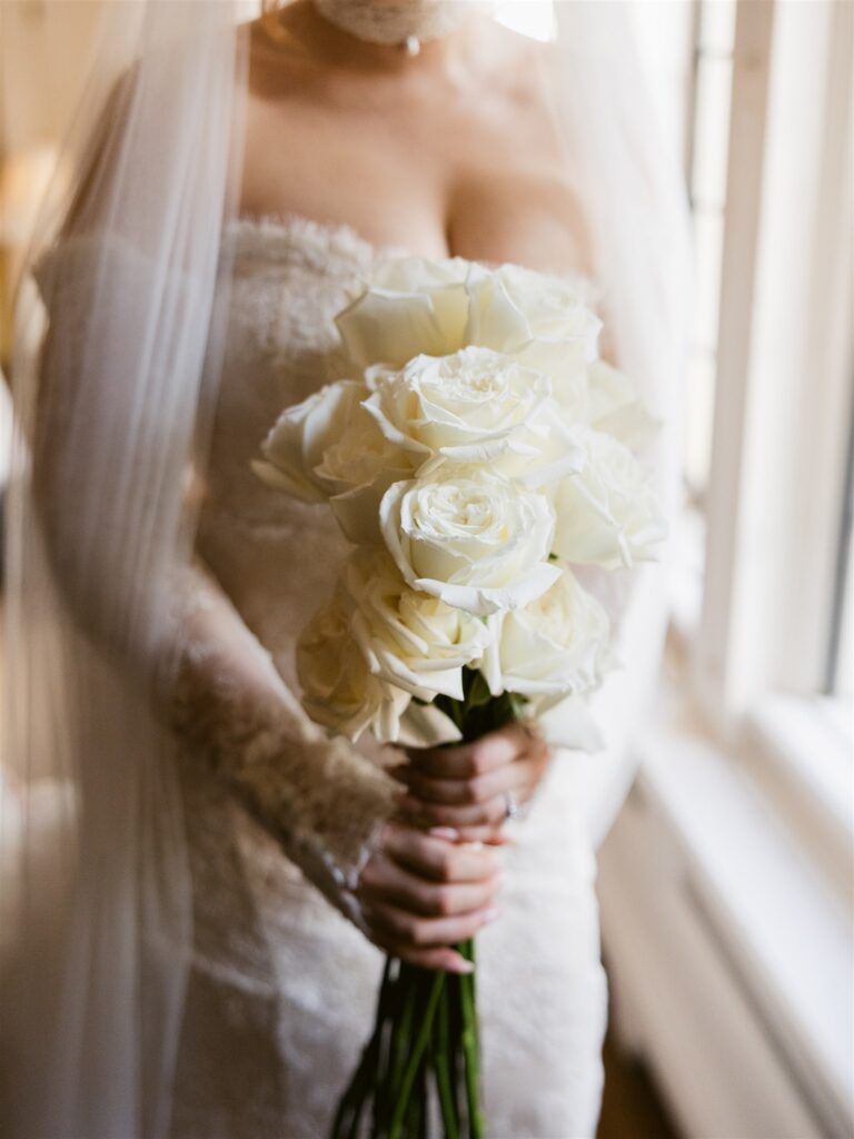 Close up shot of a bride holding her romantic white rose wedding bouquet.