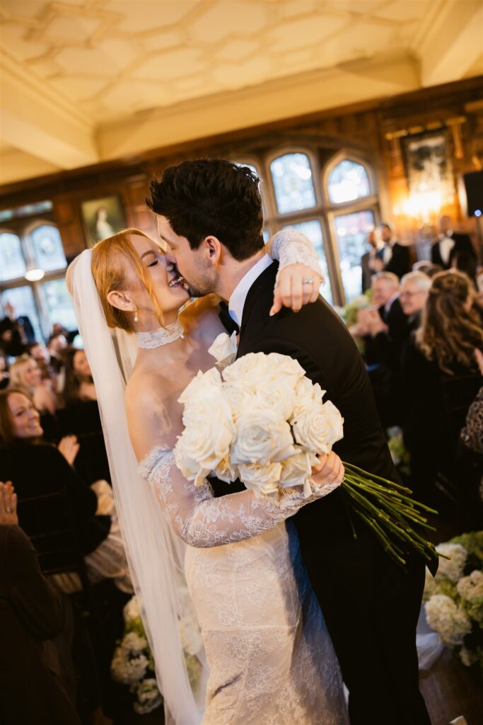 Bride and groom sharing a kiss at the end of the aisle during their Great Hall wedding ceremony at Thornewood Castle.
