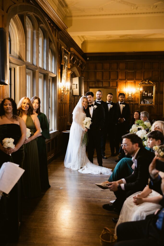Bride and groom listening to speech during their Great Hall wedding ceremony at Thornewood Castle.