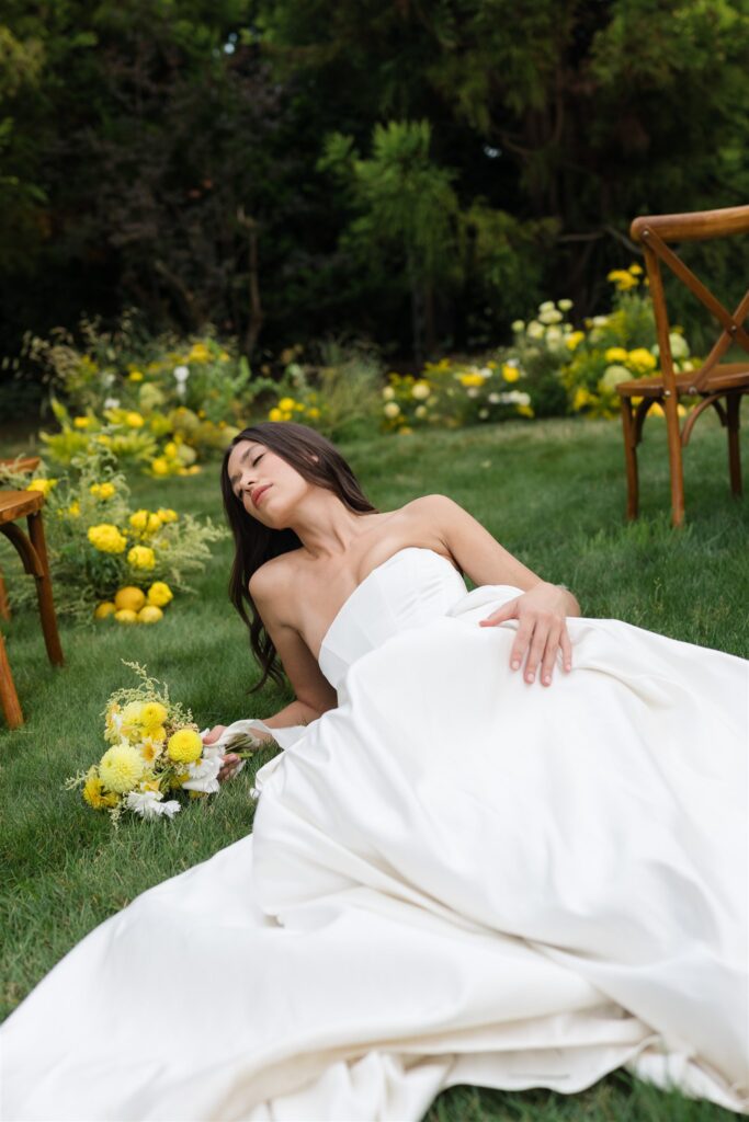Bride laying on grass with bouquet in whimsical bridal editorial at Briarwood Estate wedding.