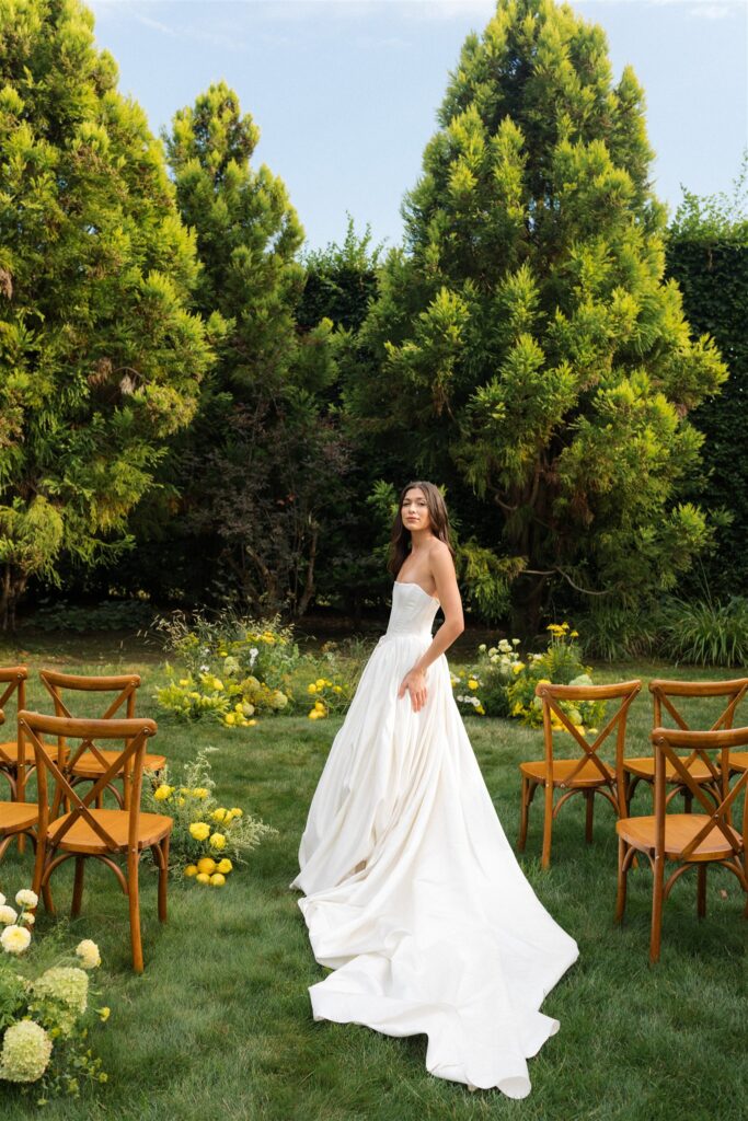 Bride standing in garden ceremony space at Briarwood Estate wedding with yellow florals and greenery.