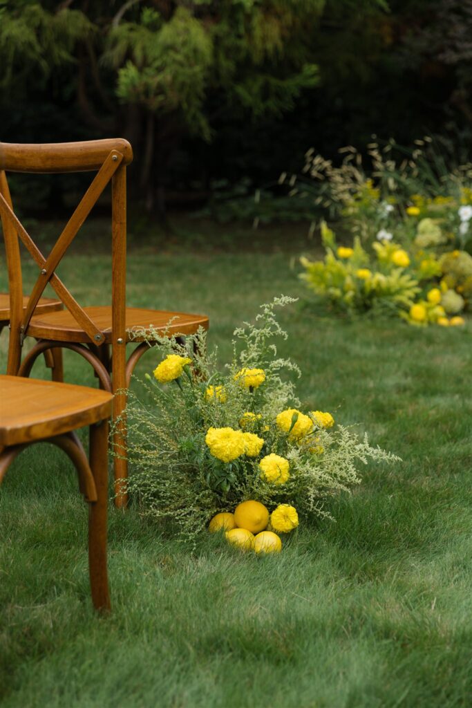 Yellow floral ceremony arrangement with lemons and wooden chairs at Briarwood Estate wedding.