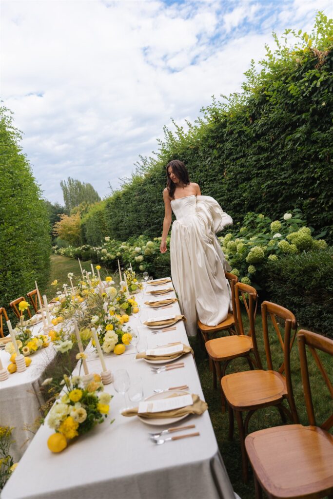 Bride standing in front of reception tables with yellow florals at Briarwood Estate wedding.