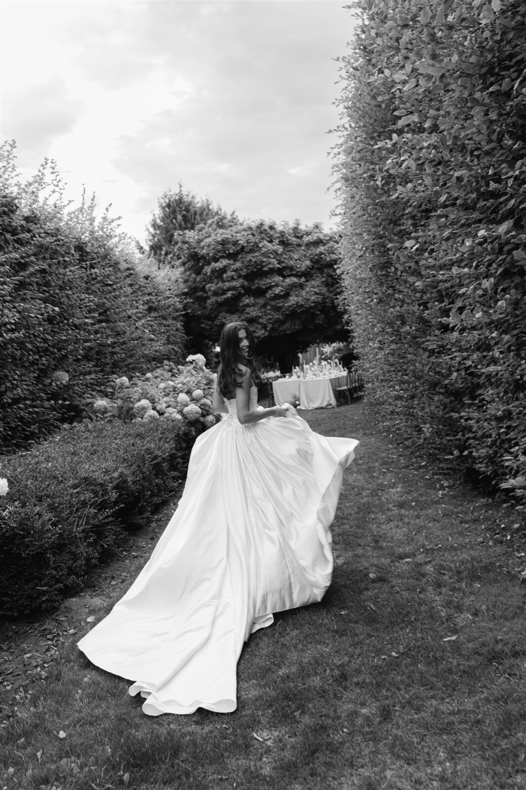 Black and white photo of bride walking through garden reception space at Briarwood Estate wedding.