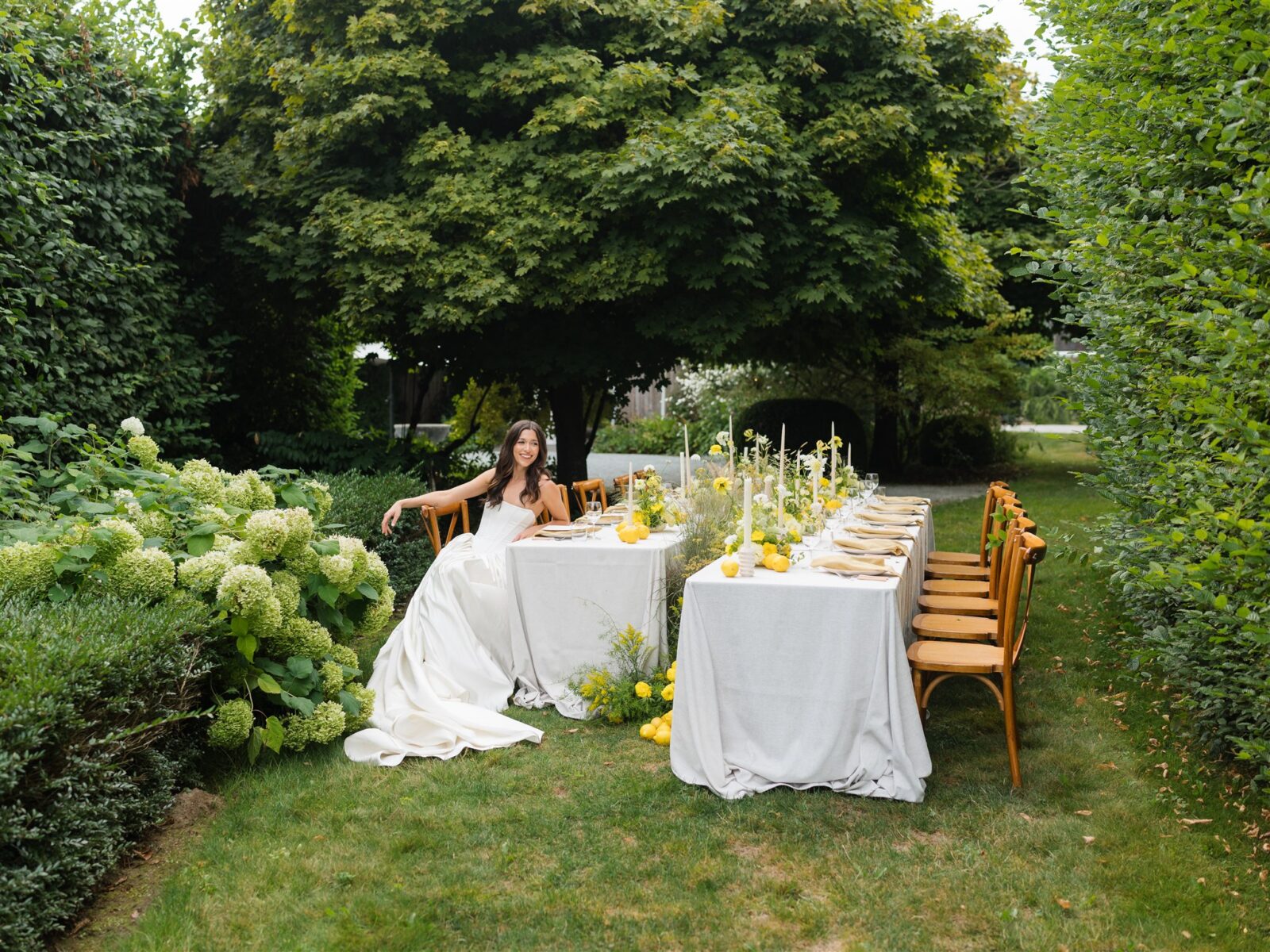 Bride sitting at a styled wedding reception table setup in a garden.