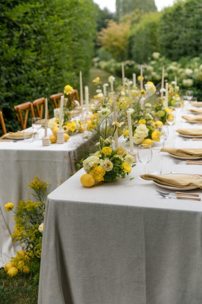 Wedding reception table with yellow floral centerpieces and candles.