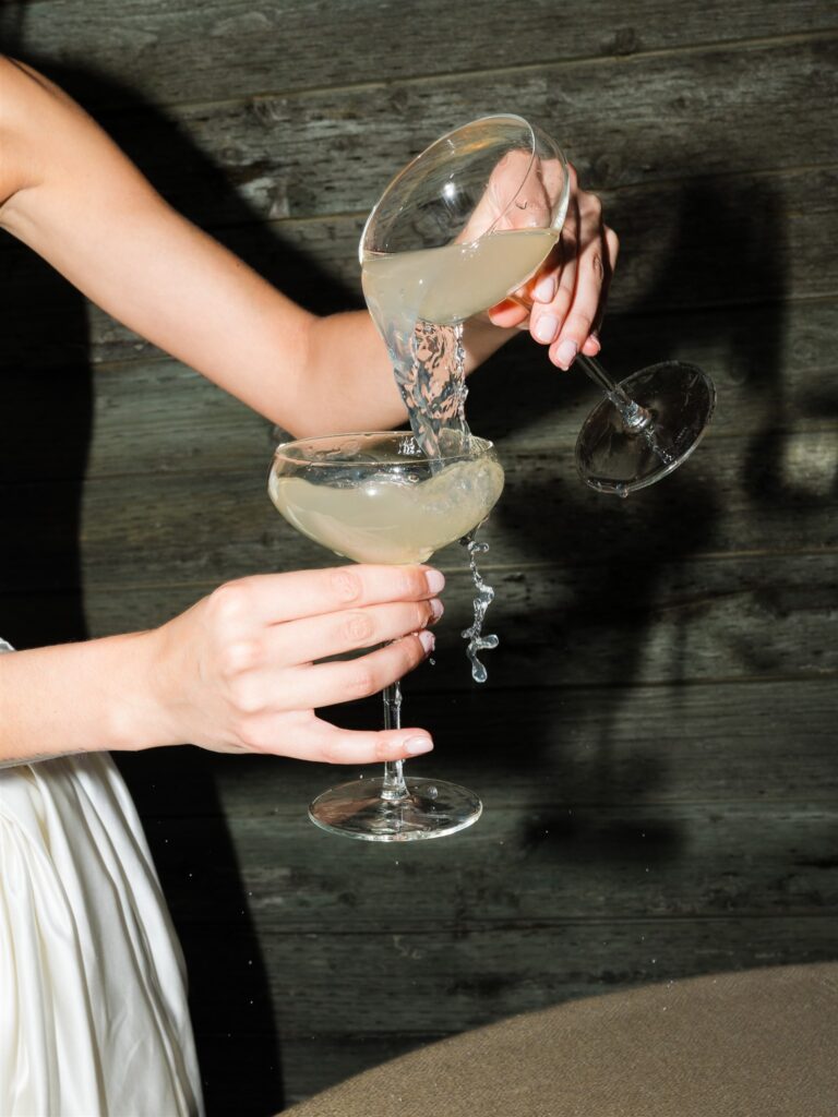 Bride pouring cocktails at reception table.