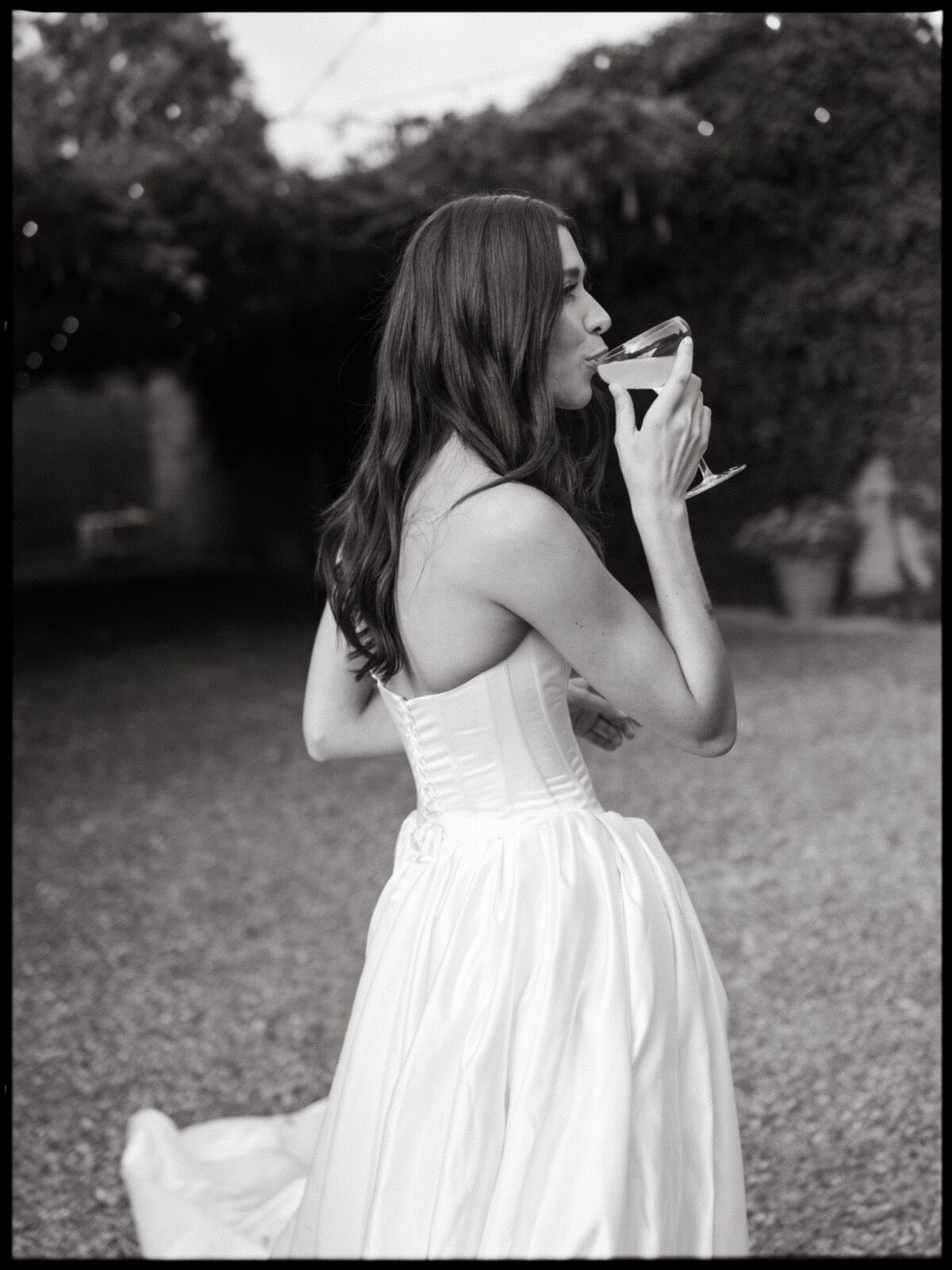 Black and white portrait of a bride drinking a cocktail during the reception.