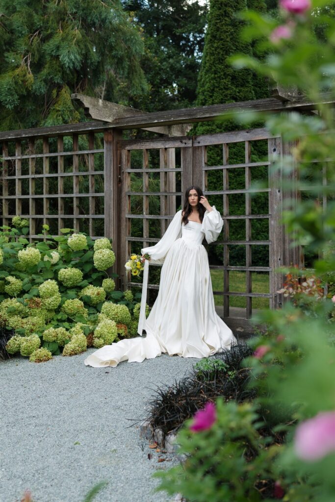 Bride standing at wooden garden gate with hydrangeas at Briarwood Estate wedding rose garden in Washington.