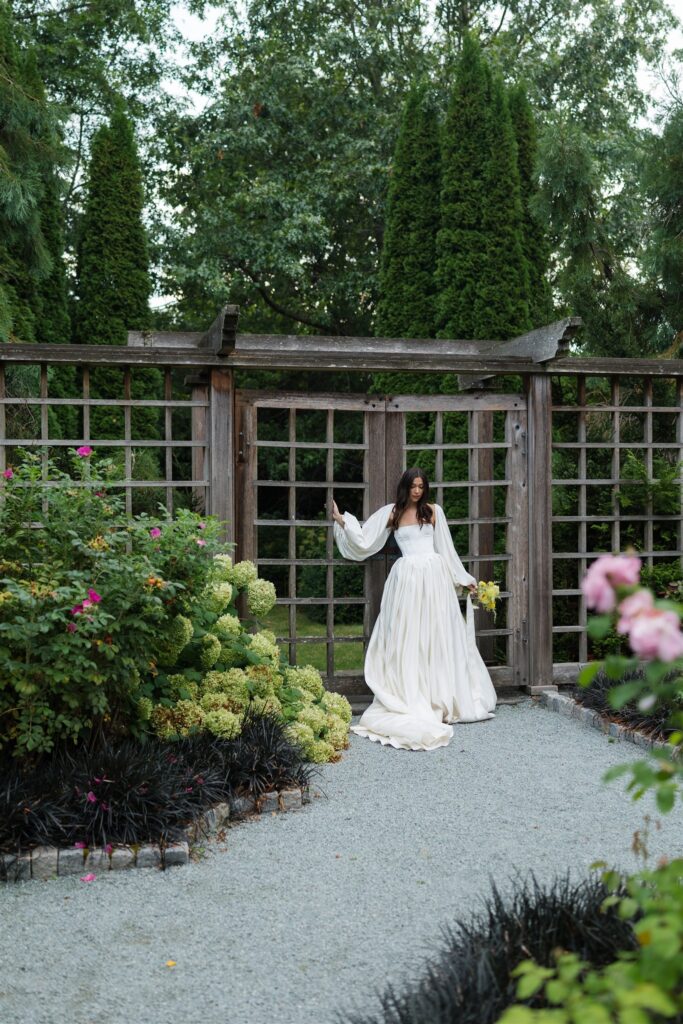 Bride standing at garden gate with lush greenery and florals at Briarwood Estate wedding in Washington.