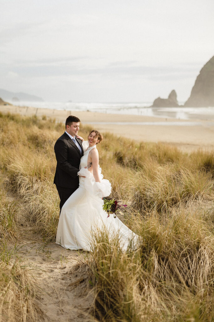 Bride and groom posing in the beach grass at golden hour for their Cannon Beach elopement photos.