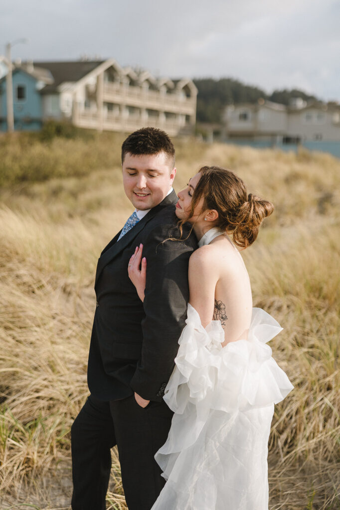 Bride smiling up at the groom as they standing the beach grass along the Oregon Coast.