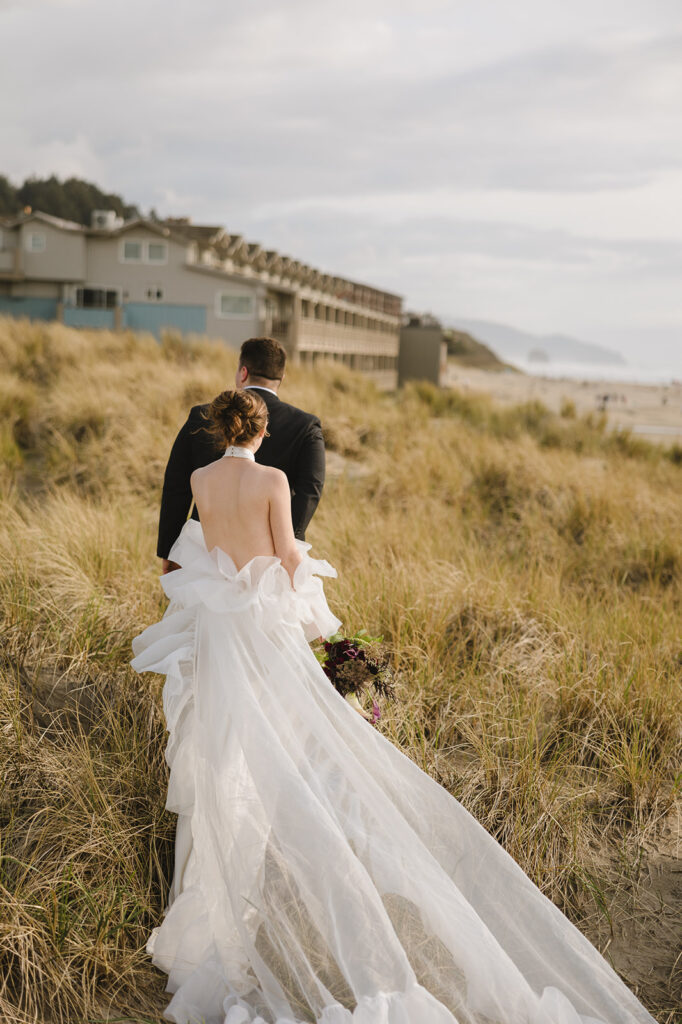 Bride and groom walking in the beach grass during their Cannon Beach elopement.