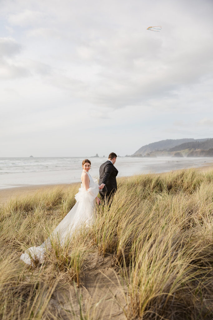 Bride and groom walking alone the beach grass for their Cannon Beach elopement.