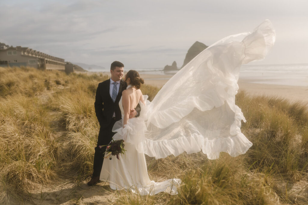 Filmy inspired Cannon Beach elopement photo with the brides train flowing up in the wind.