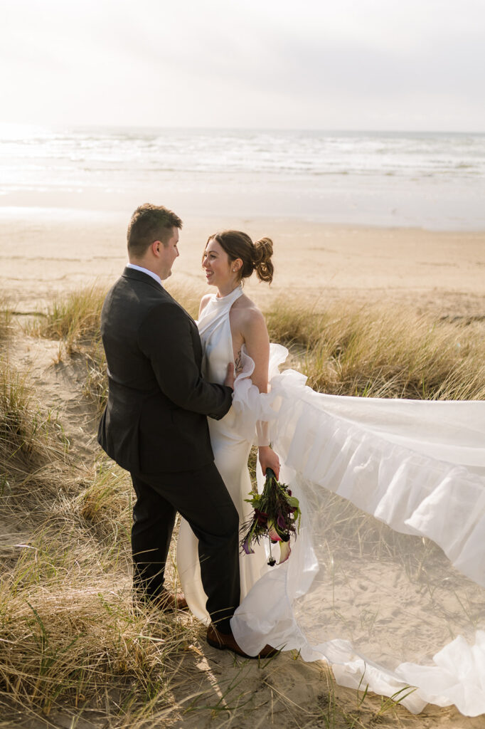 Bride and groom posing in the beach grass at golden hour for their Cannon Beach elopement photos.