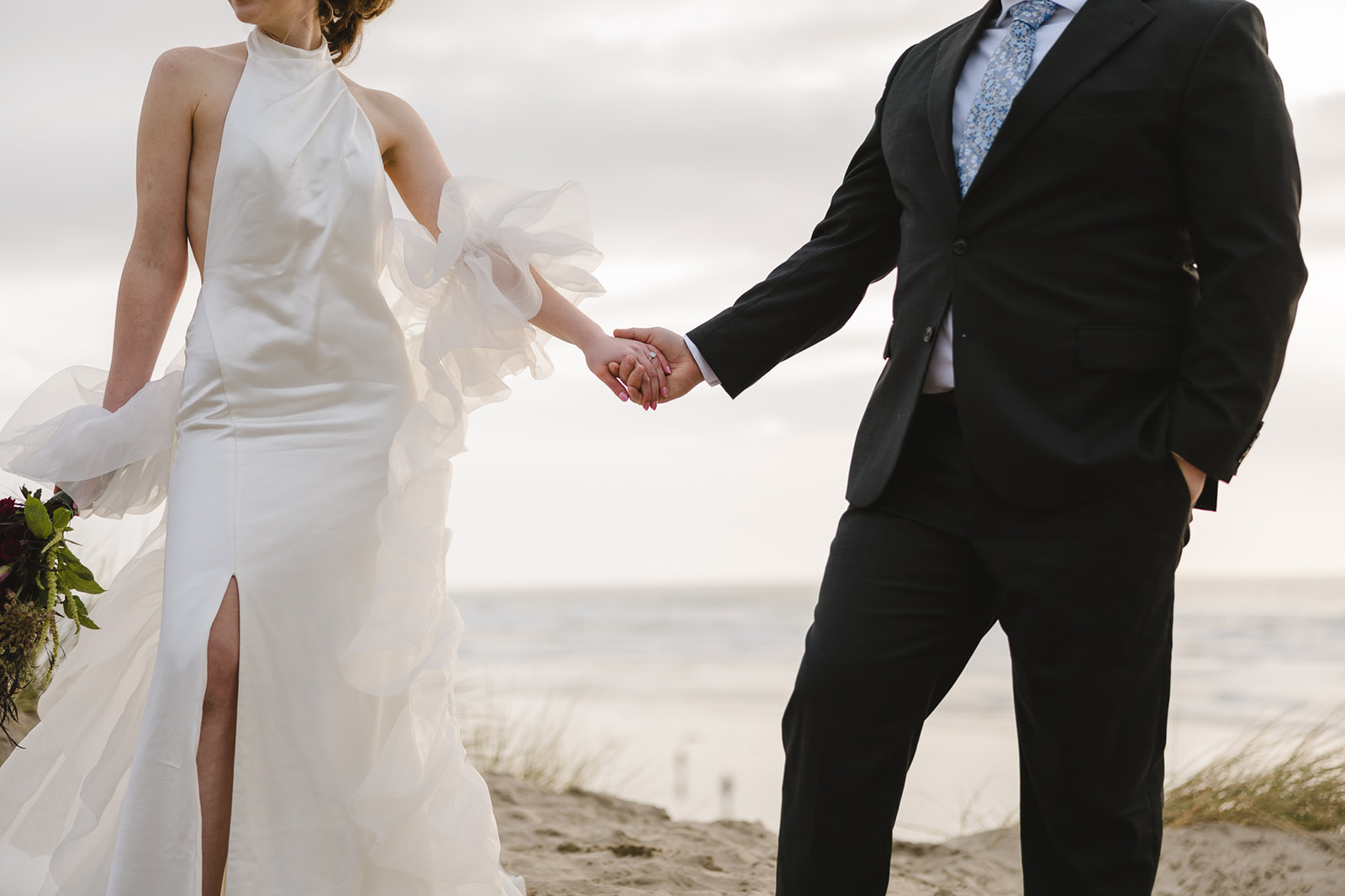 Wide close up shot of a bride and groom holding hands.