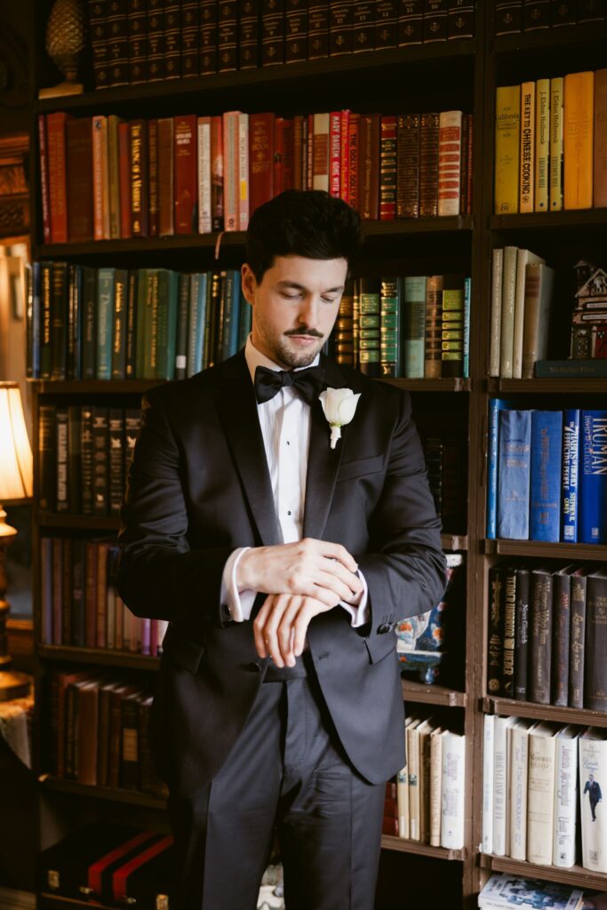 Indoor grooms portrait in front of a bookshelf in one of the suites at Thornewood Castle wedding venue in Lakewood, WA.