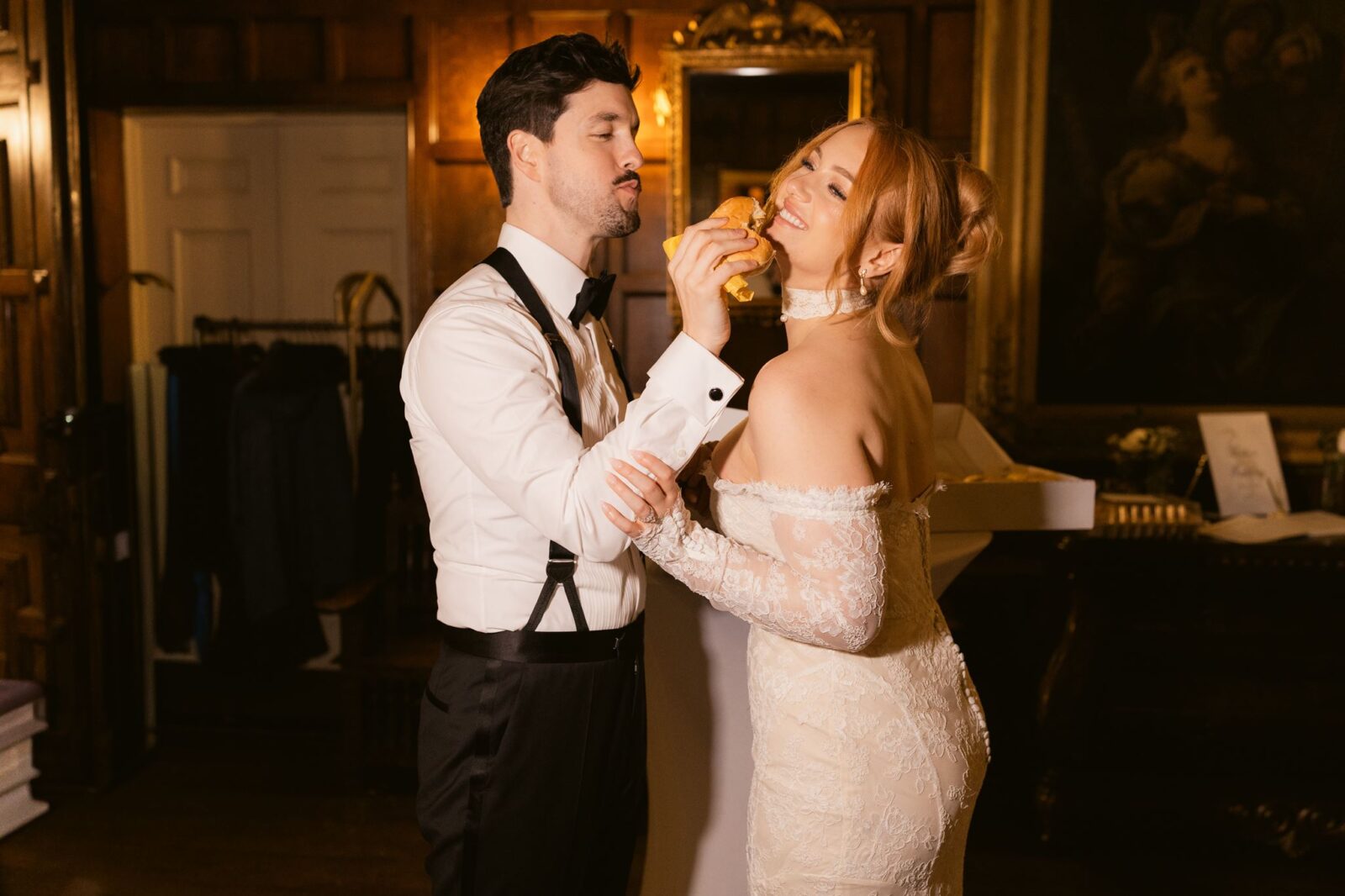 Bride and groom feeding each other burgers during their late-night wedding reception in the ballroom.