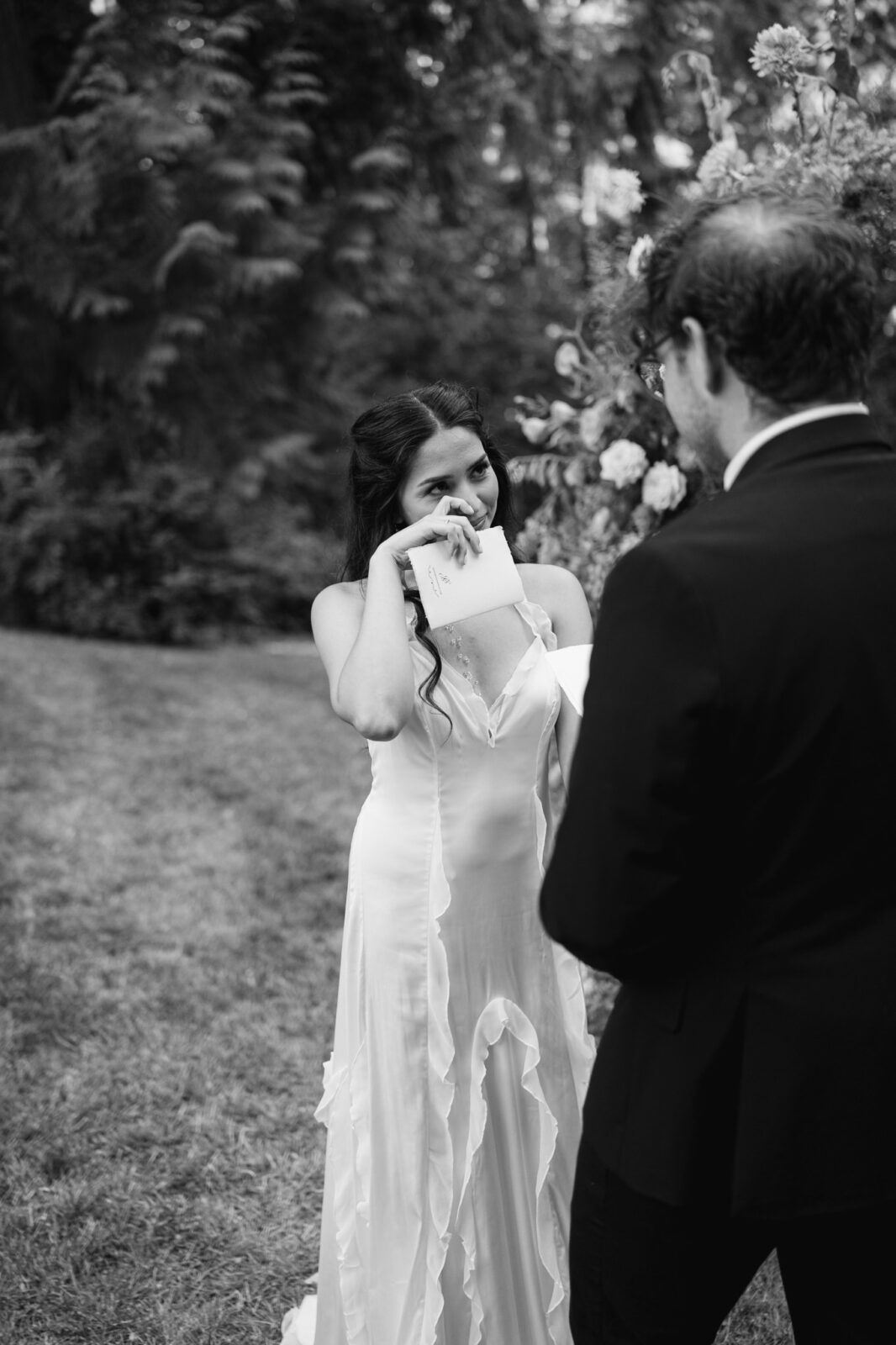 Black and white photo of bride wiping tears during ceremony at Foxglove Lodge Vashon Island.