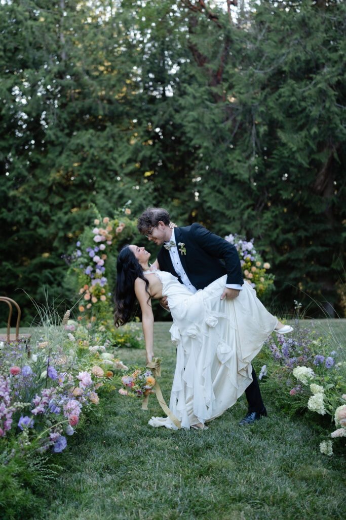 Groom dips bride in the floral ceremony aisle at Foxglove Lodge Vashon Island.