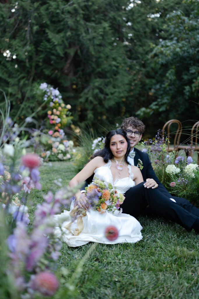 Couple sitting together in the floral ceremony aisle at Foxglove Lodge Vashon Island.