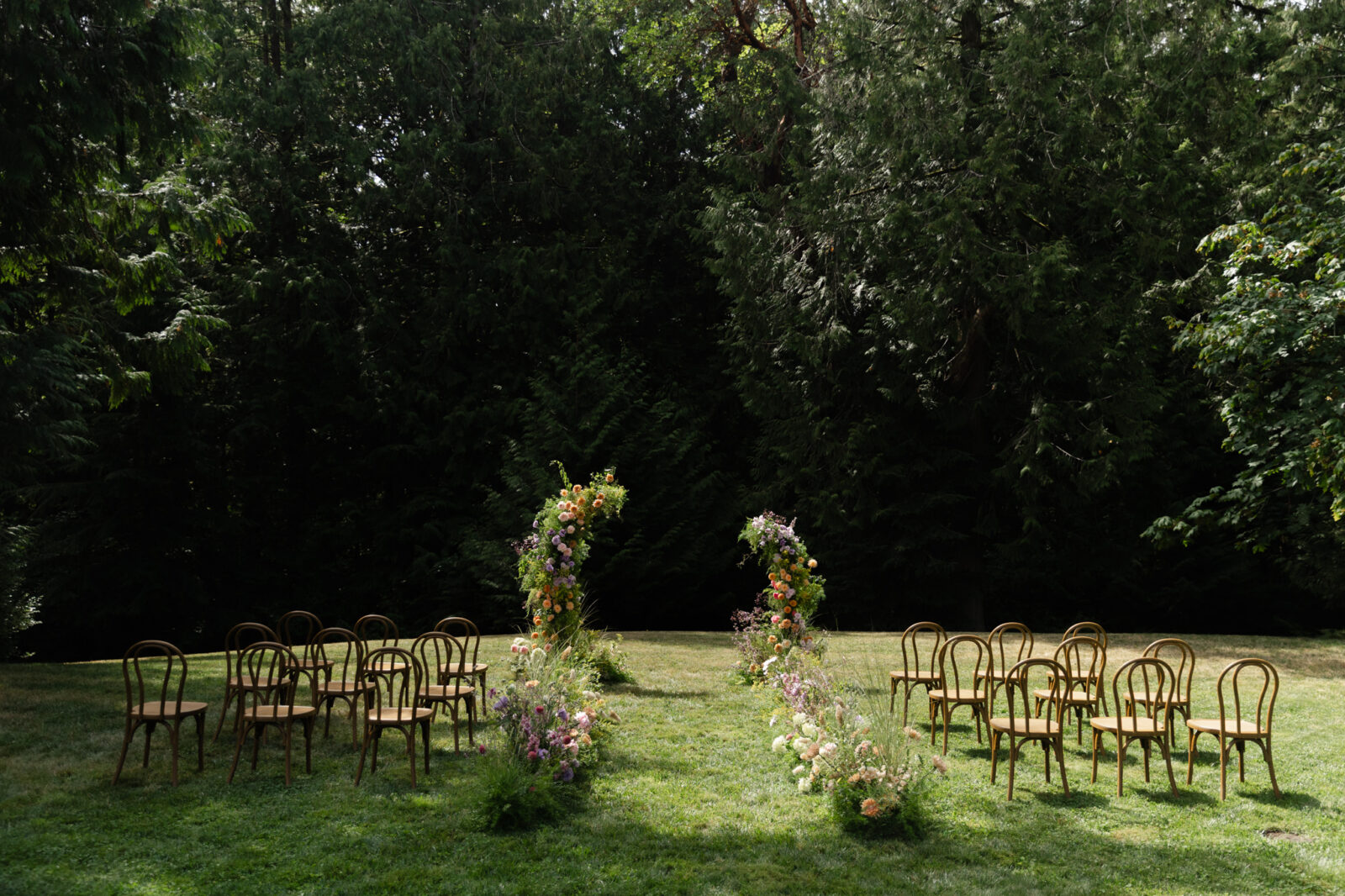 Whimsical ceremony setup with colorful floral aisle on the Amphitheater Lawn at Foxglove Lodge Vashon Island.