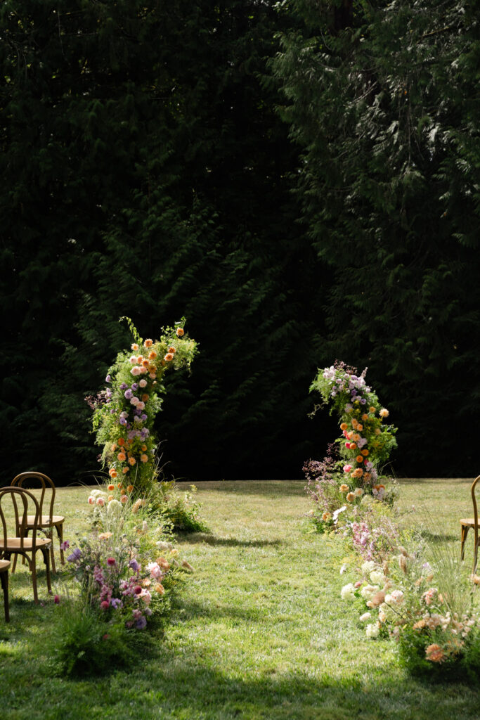 Whimsical ceremony setup with colorful floral aisle on the Amphitheater Lawn at Foxglove Lodge Vashon Island.