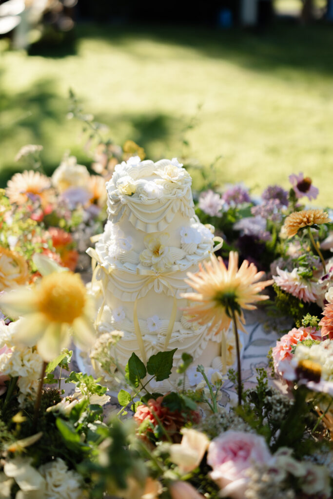 Whimsical wedding cake surrounded by colorful flowers at Foxglove Lodge Vashon Island.