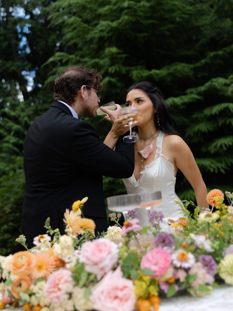 Couple giving each other drinks of champagne from their champagne tower at Foxglove Lodge in Vashon Island, WA.