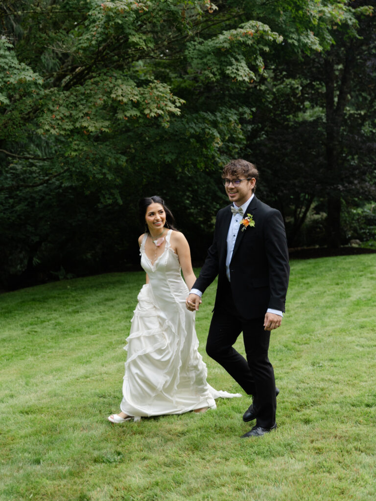 Couple holding hands and walking on the lawn at Foxglove Lodge in Vashon Island, WA.