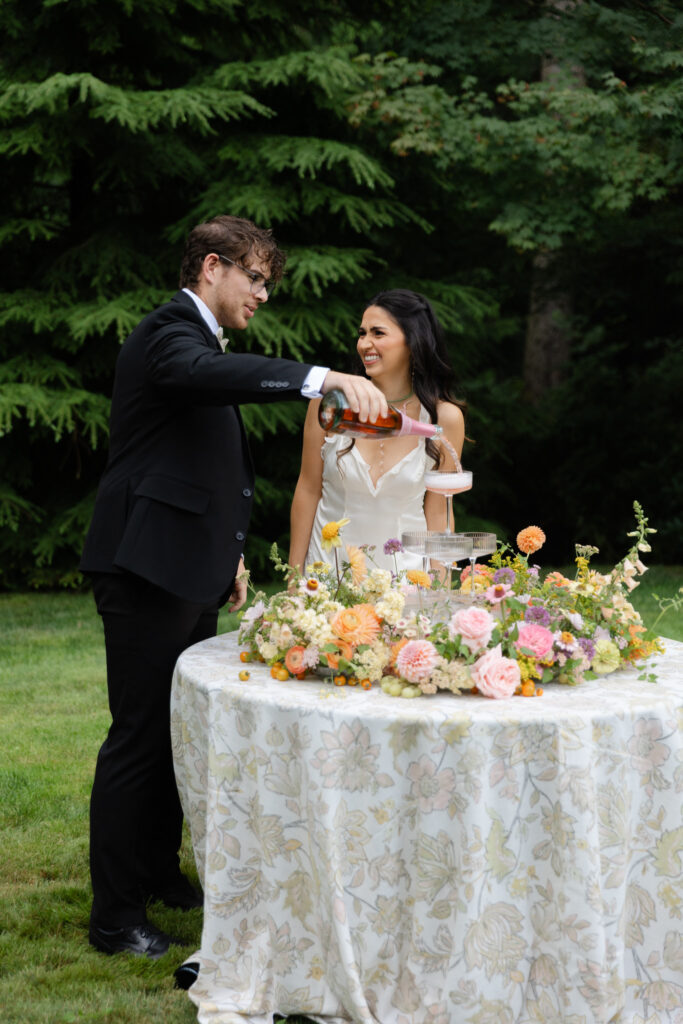 Couple pouring into a champagne tower on the Central Celebration Lawn at Foxglove Lodge Vashon Island.