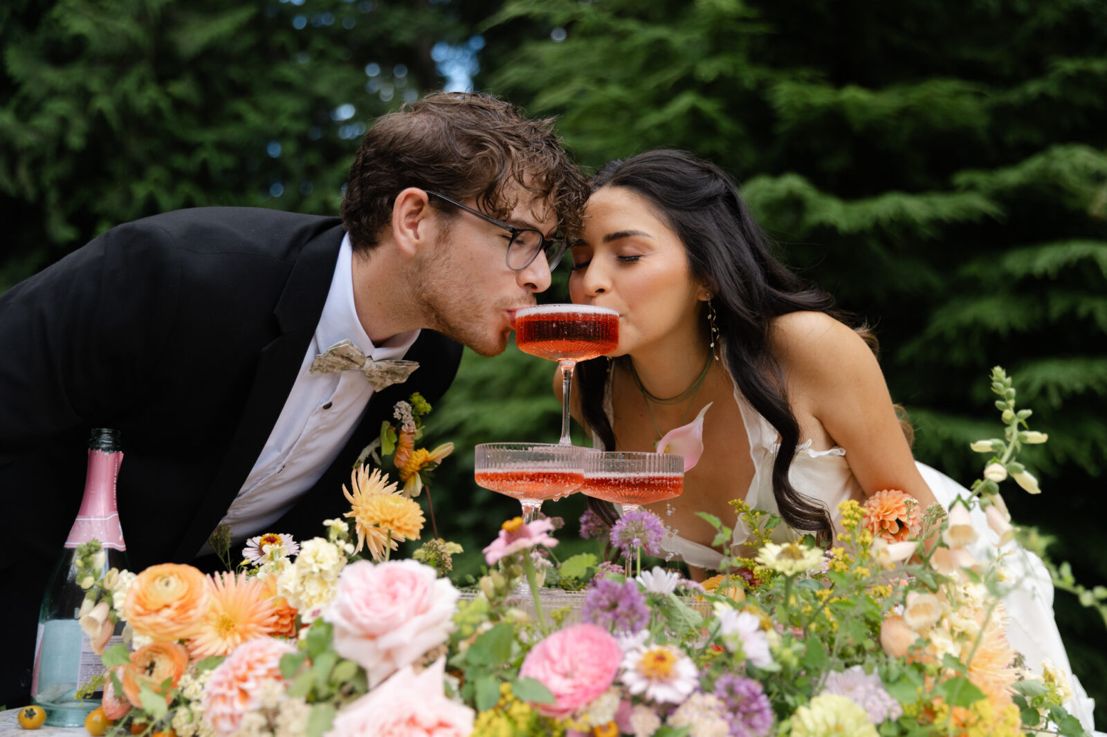 Close up shot of a couple drinking from champagne tower during whimsical wedding shoot at Foxglove Lodge Vashon Island.