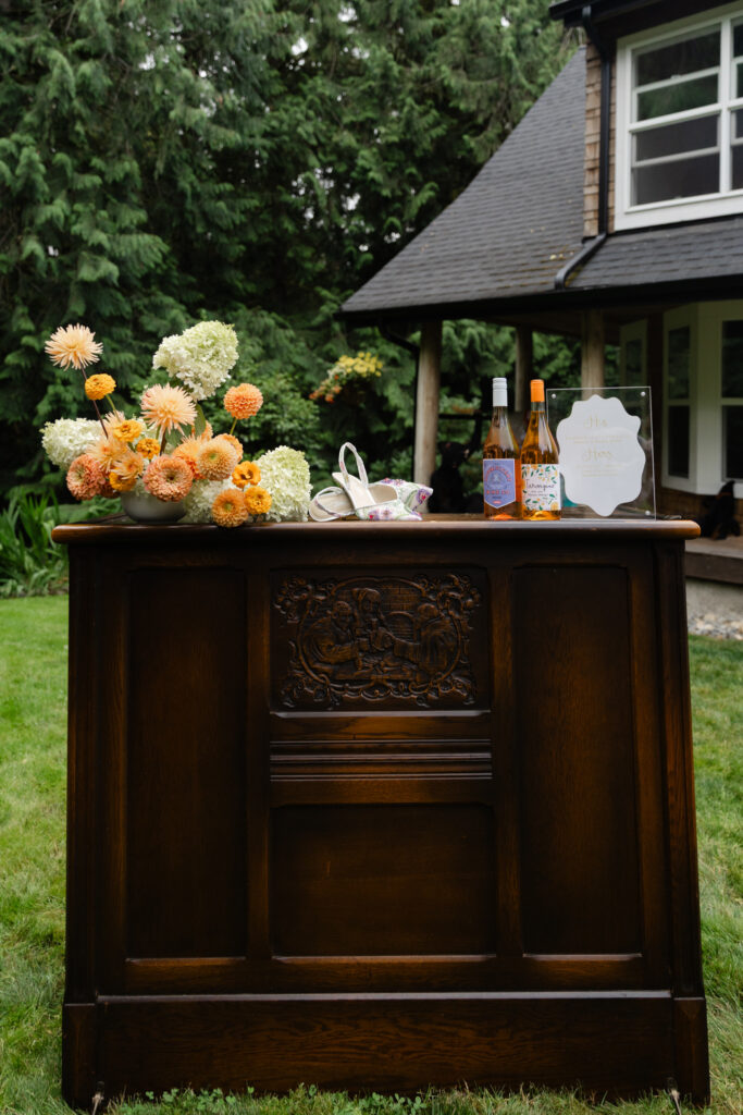 Cocktail bar with flowers, shoes, wine, and signature drink sign at Foxglove Lodge Vashon.