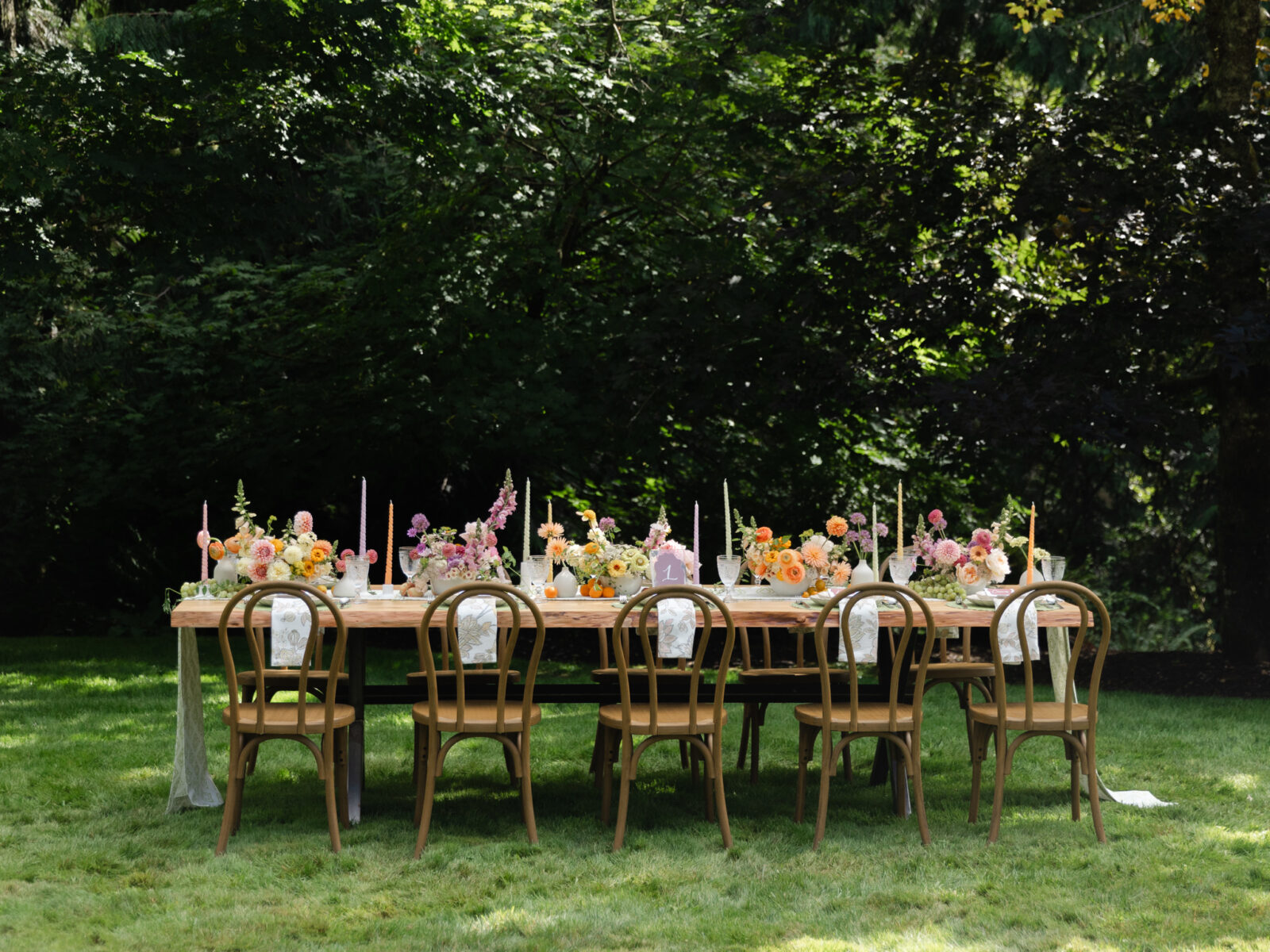 Long wedding reception table with wood chairs and colorful flowers at Foxglove Lodge Vashon.