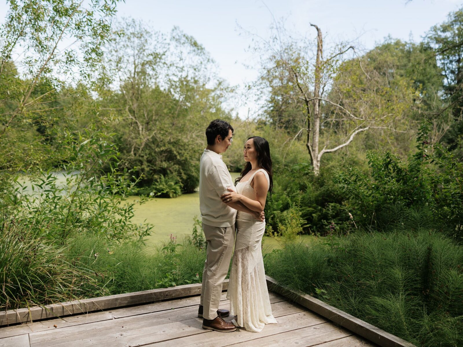 Couple posing on a deck area by a pond at Bloedel Reserve for their engagement photos.