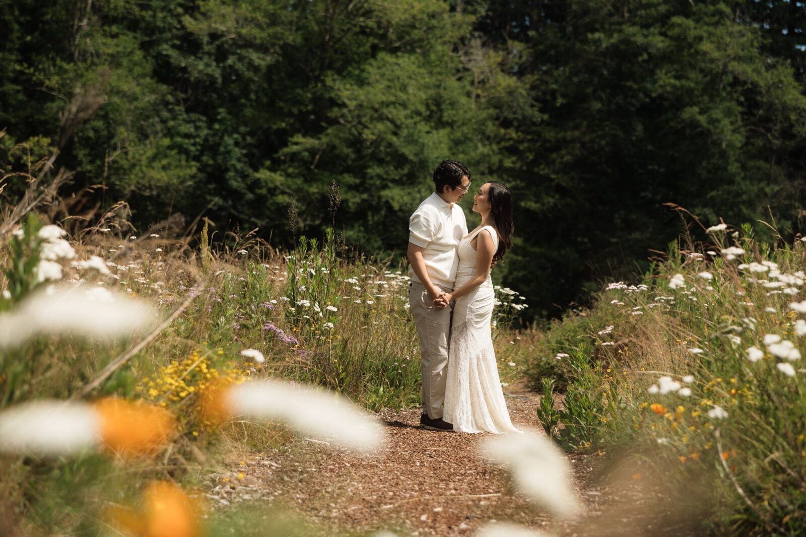 Couple smiling at each other as they pose in a patch of wildflowers at Bloedel Reserve.
