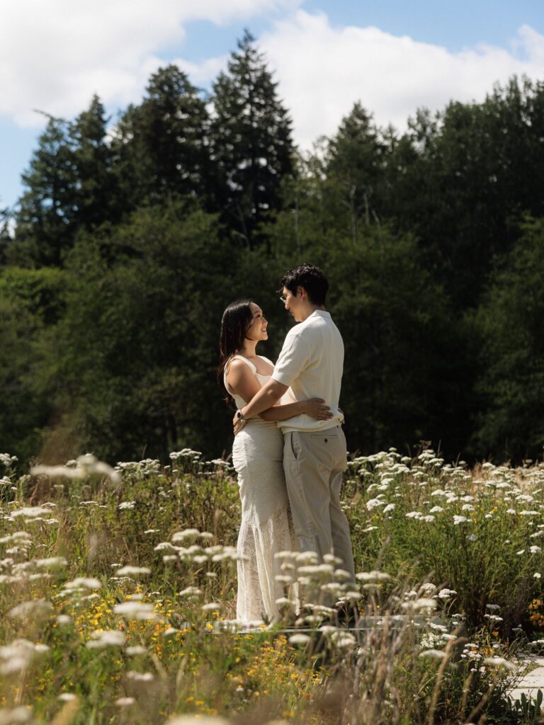 Couple embracing in a patch of wildflowers at Bloedel Reserve for their engagement photos.