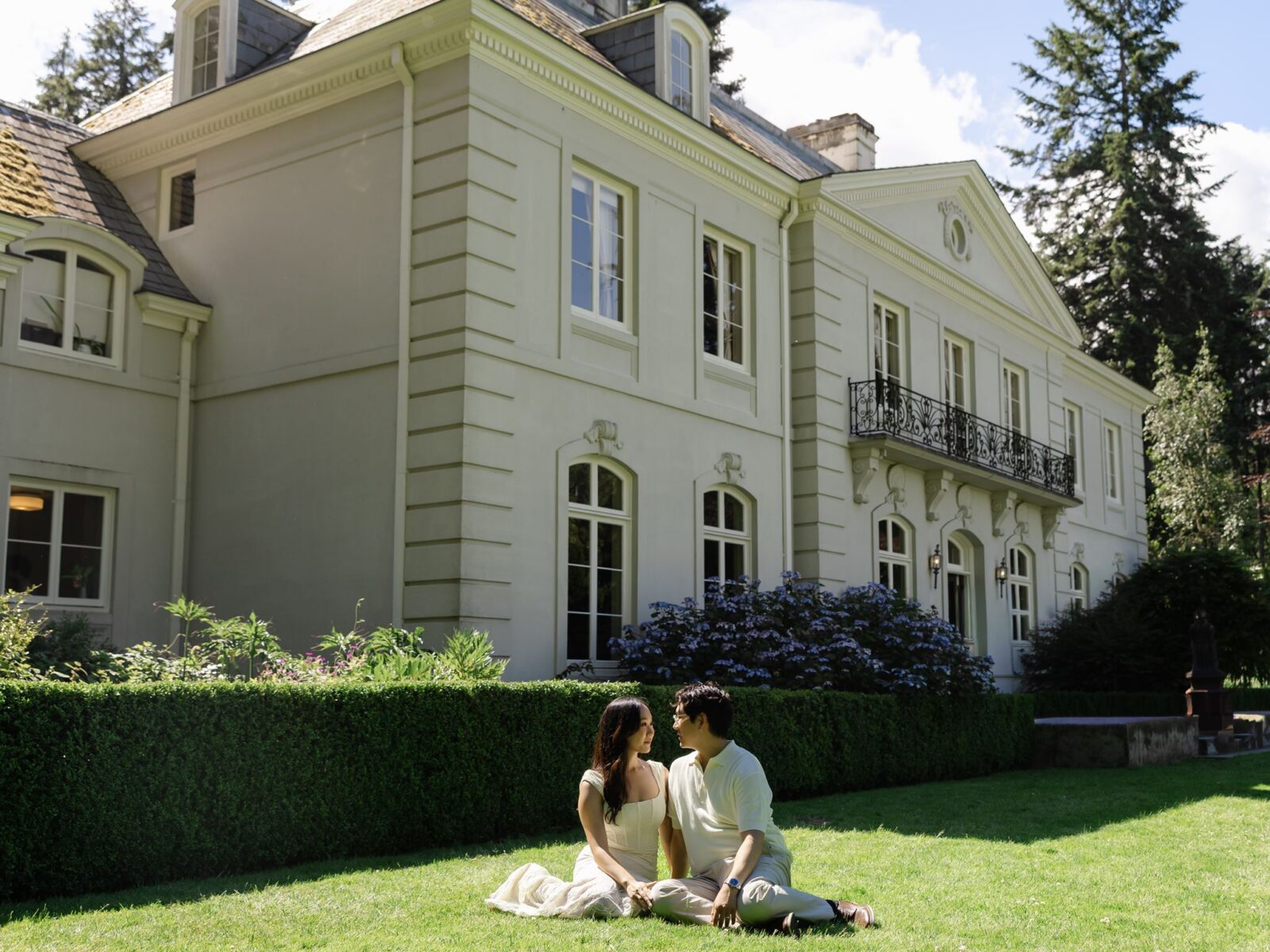 Couple sitting in the grass in front of The Residence at Bloedel Reserve in Washington.